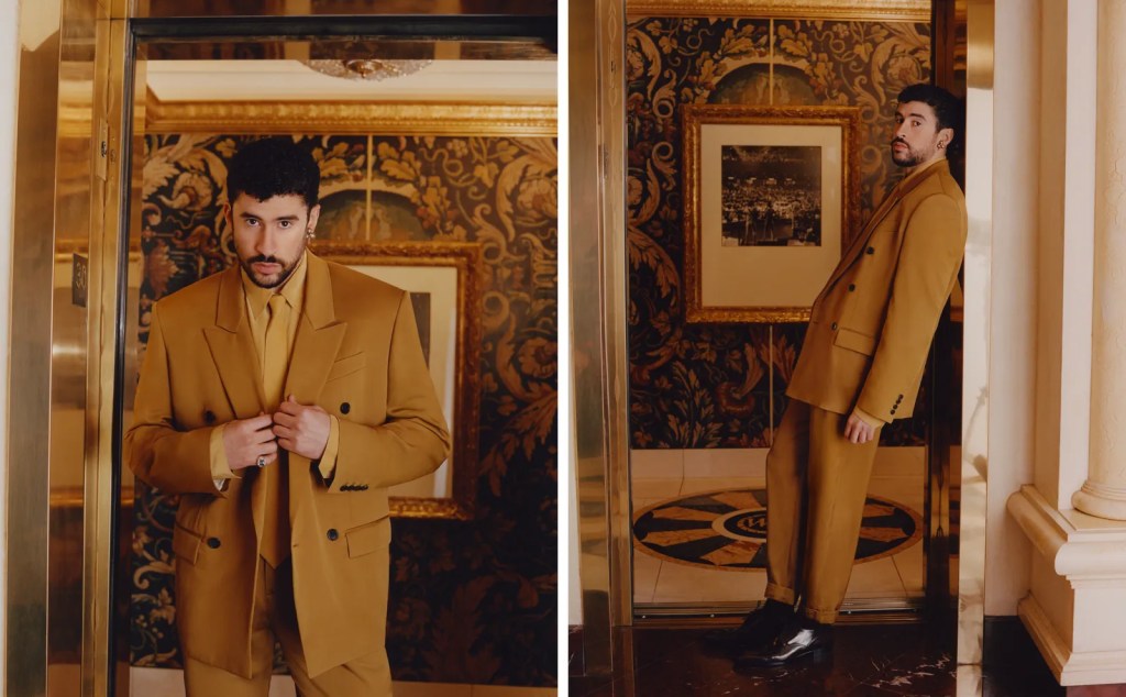 Bad Bunny i gul dress og høye boots med hæler i et rom med gullramme-bilde og tepper og heis. 