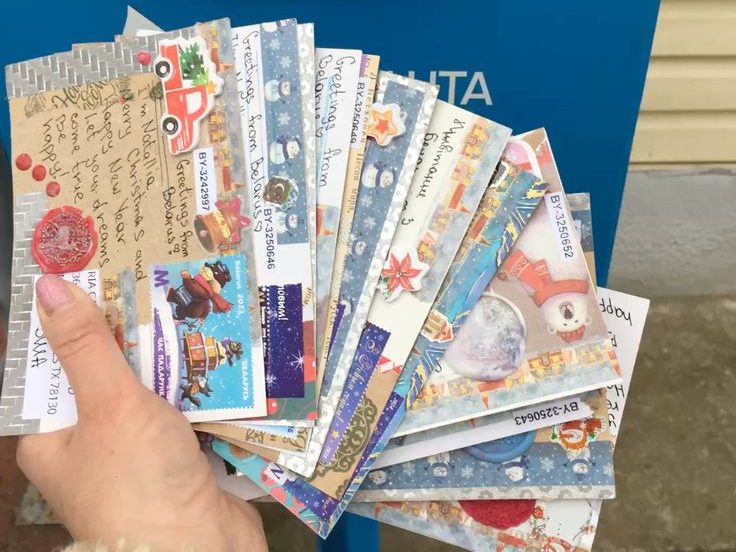 Brev med klistremerker foran en postkasse. 