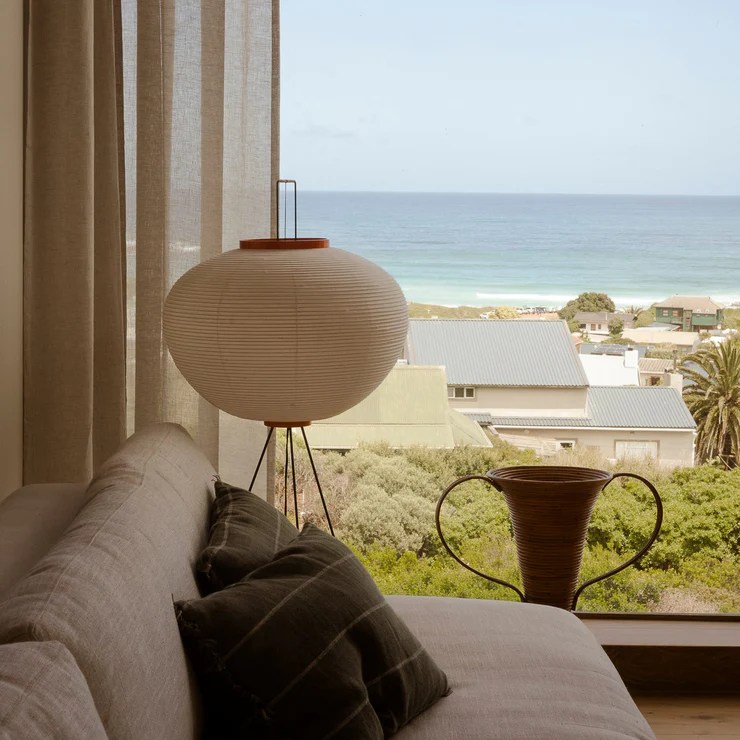 Papirlampe som står på benken ved vinduskarmen. Utsikt mot blått hav og hus. 