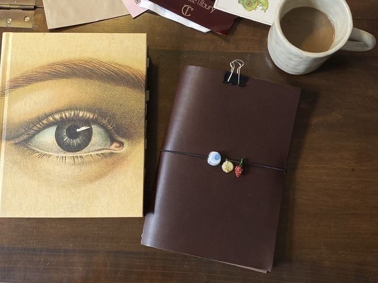 Bok md øyne på, og en notatbok på en desk med en kaffekopp.
